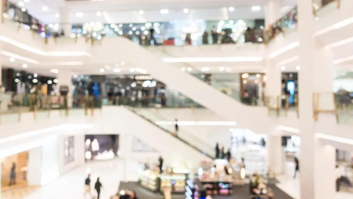 The bright atrium of a luxury shopping mall, storefronts rising over several levels