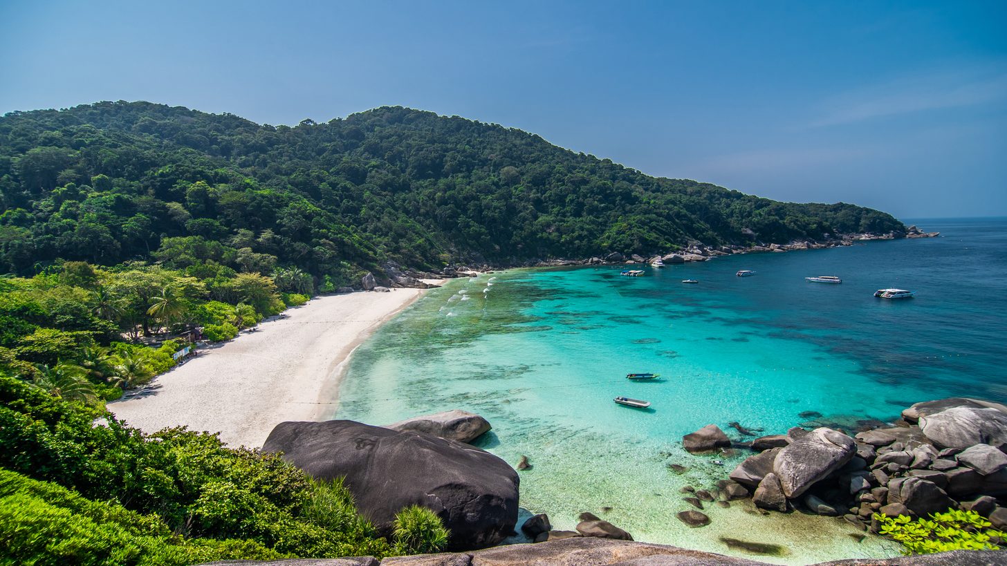 Granite boulders and a white-sand bay seen from the Similan Islands viewpoint, with boats anchored in turquoise water