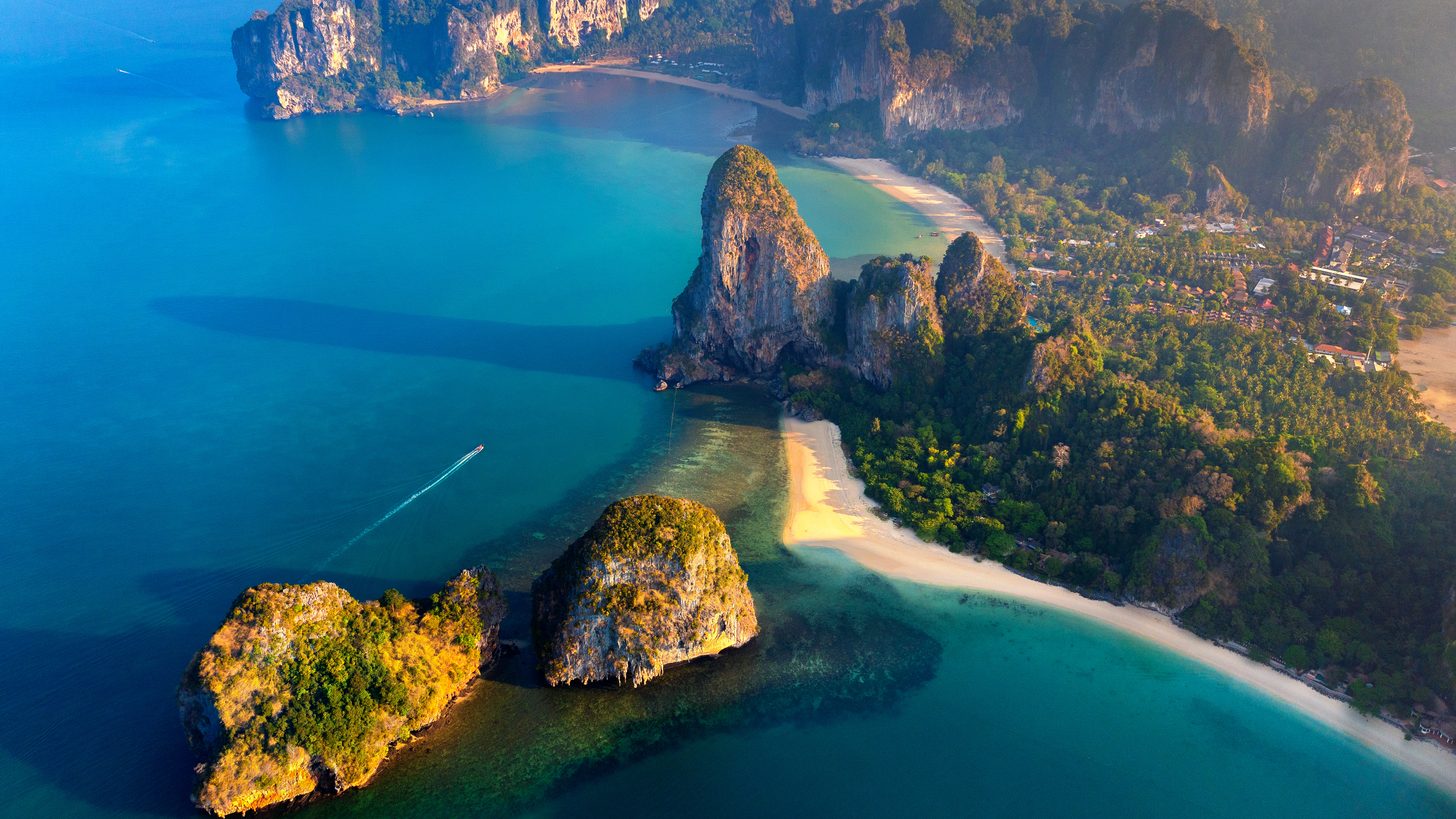 An aerial view of Railay beach in Krabi with limestone cliffs rising behind the sand