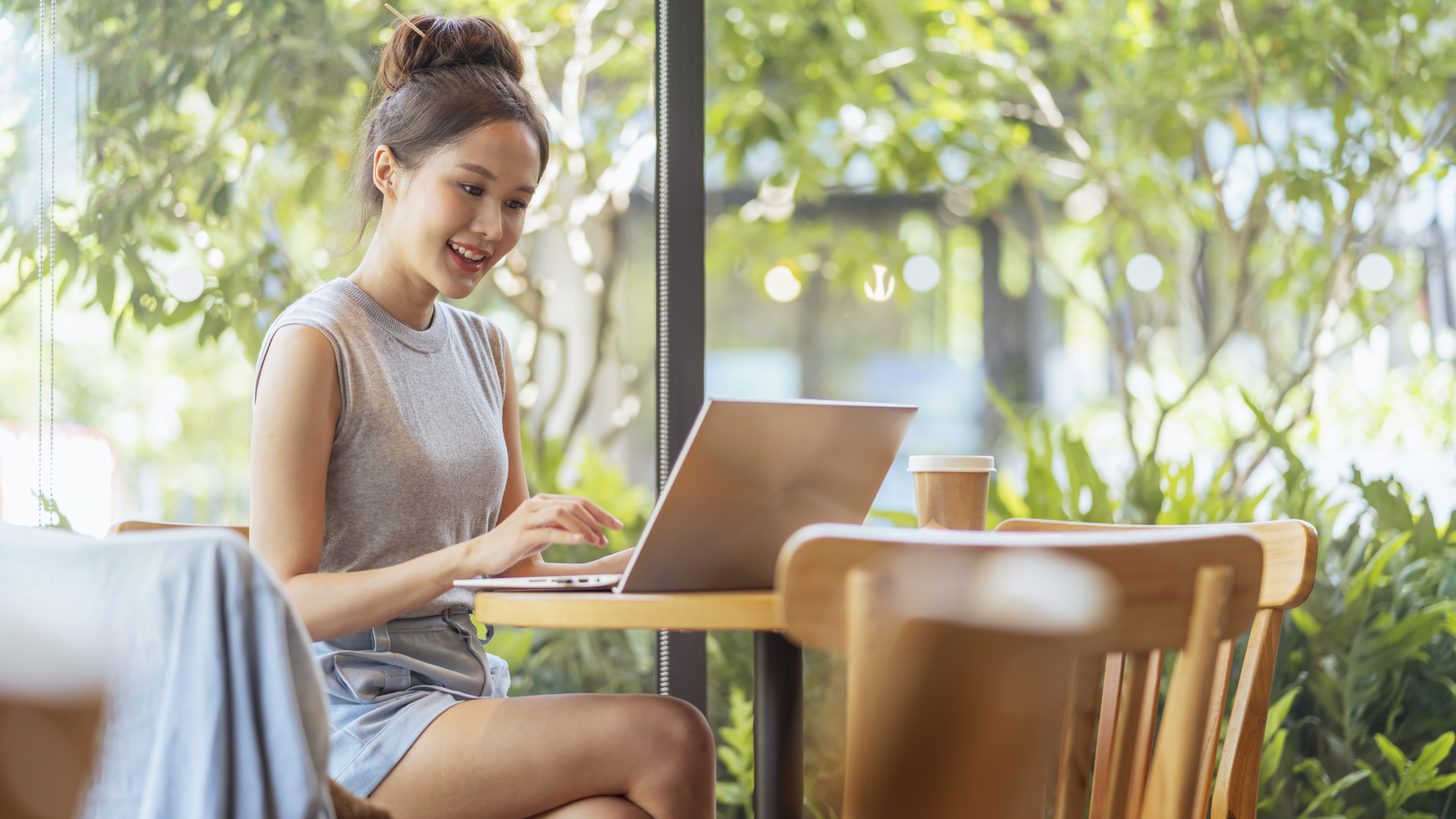 A remote worker using a laptop at a tropical café in Thailand