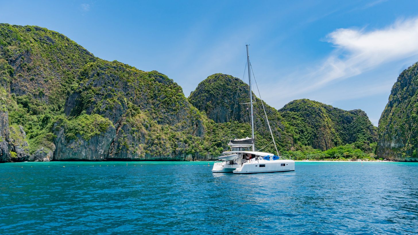 A luxury catamaran anchored in a turquoise bay among limestone cliffs