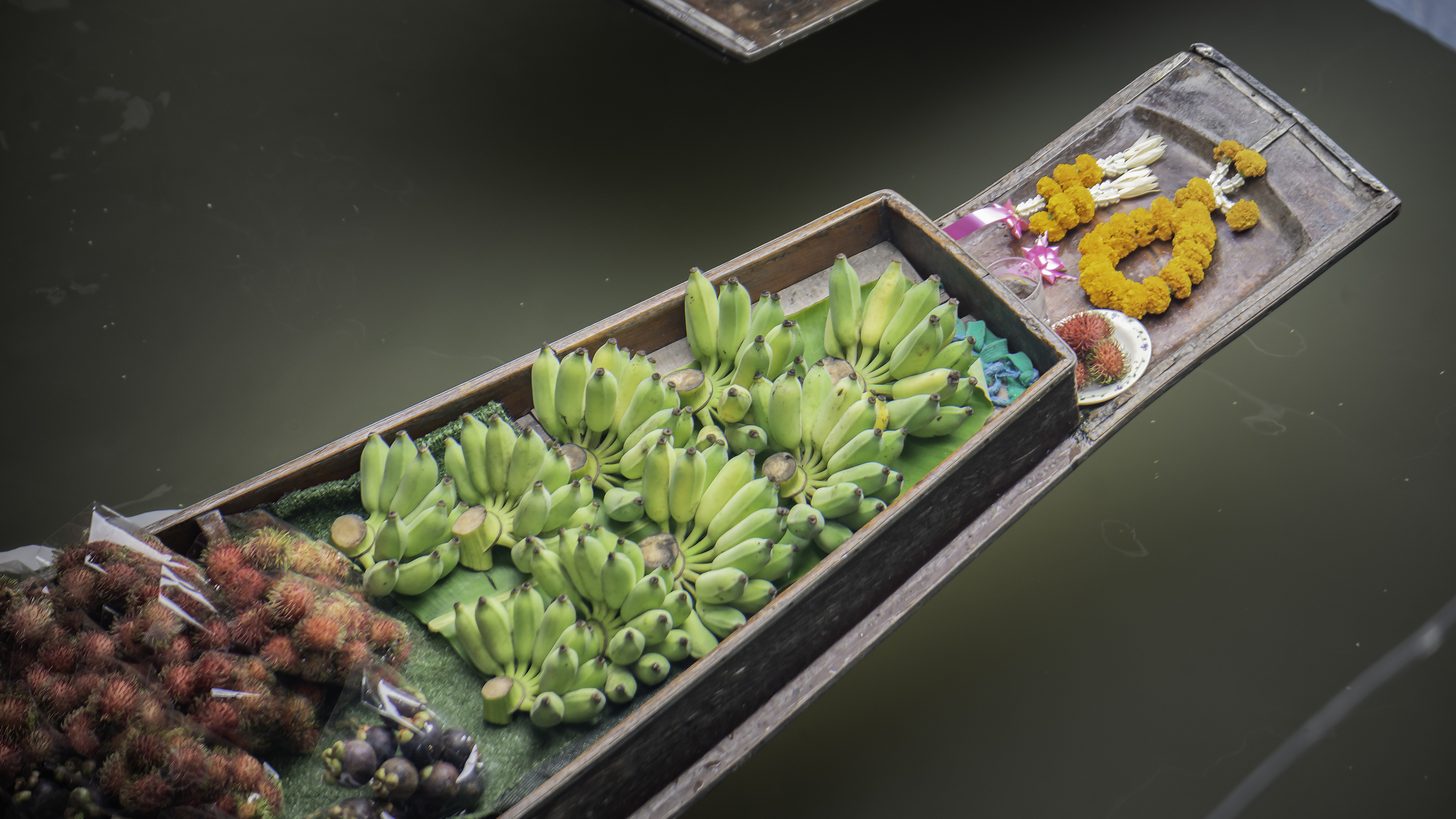 Vendors selling fruit from wooden boats at a Thai floating market