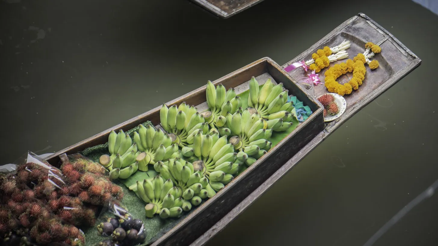 Vendors selling fruit from wooden boats at a Thai floating market