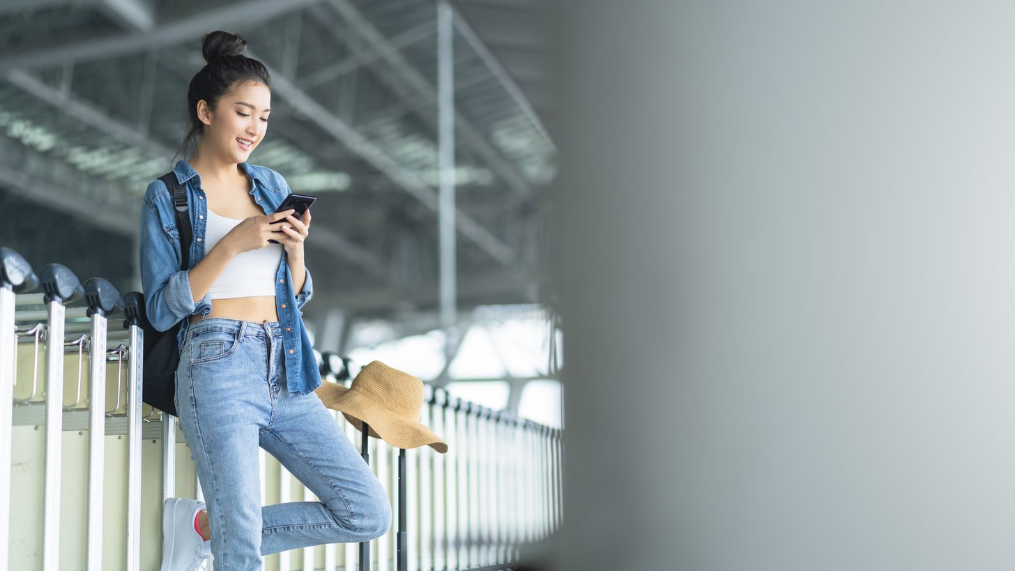 A traveller checking a taxi app on her smartphone at a station platform