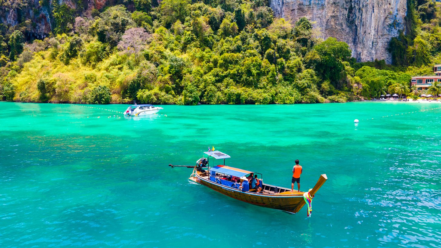 Tourist longtail boats on a turquoise Andaman bay in Thailand's high season