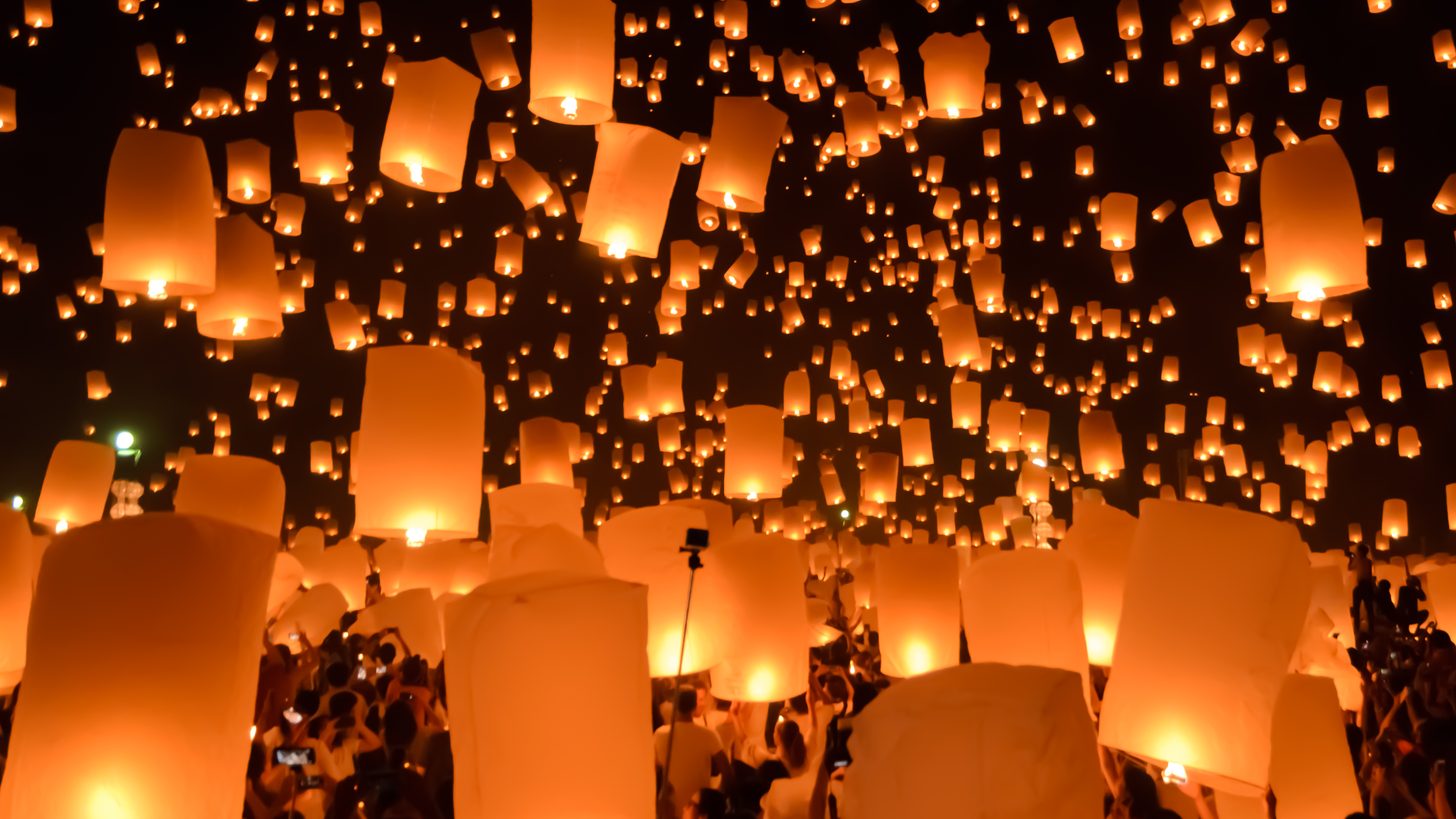 Hundreds of sky lanterns rising over the crowd at Chiang Mai's Yi Peng festival