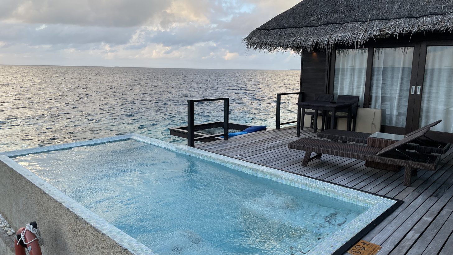 A beach resort bungalow beside an endless pool at sunset on a Thai island