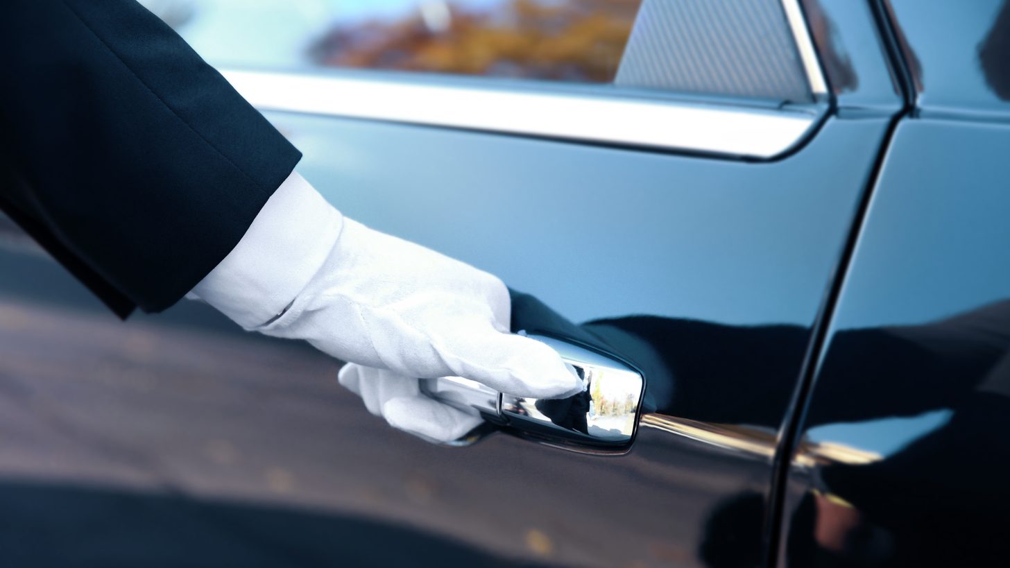 A chauffeur opening the door of a luxury car