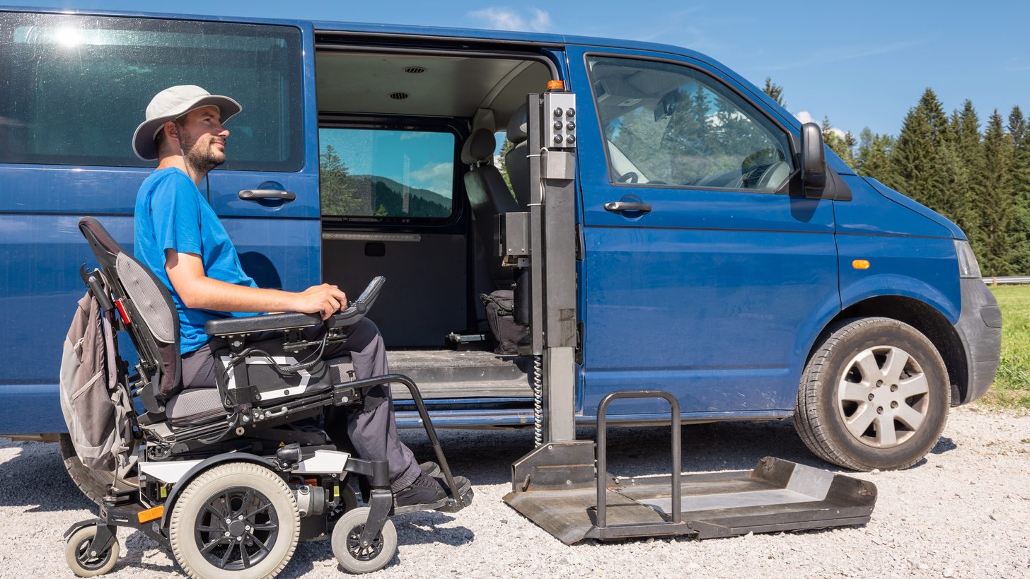 Wheelchair user using a fold-out lift to exit an adapted transport van