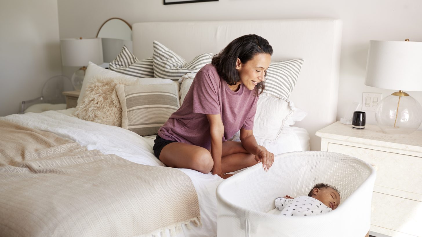 Mother watching over her baby sleeping in a hotel-room cot in Thailand