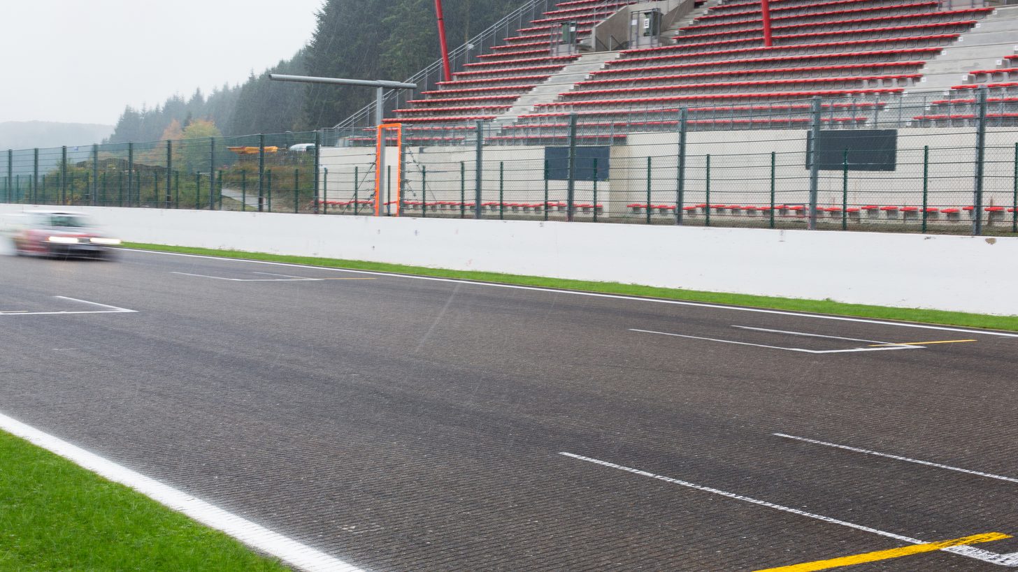 Race car on a circuit passing spectator grandstands