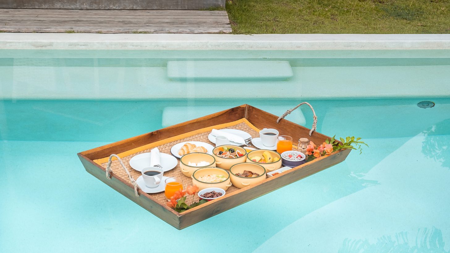 Floating breakfast tray with fruit and pastries in a villa swimming pool