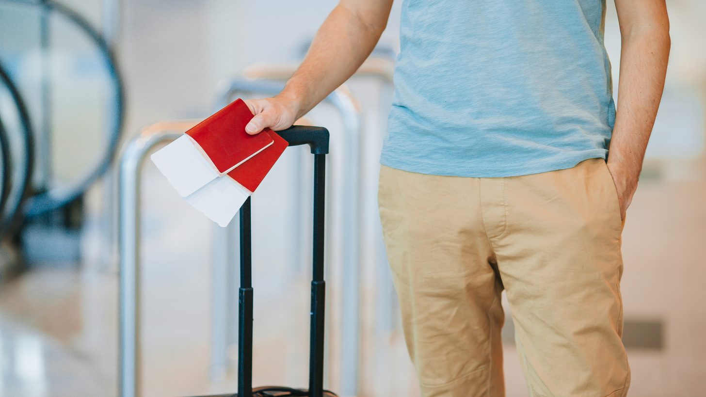 Traveller holding a boarding pass and passport at an airport gate