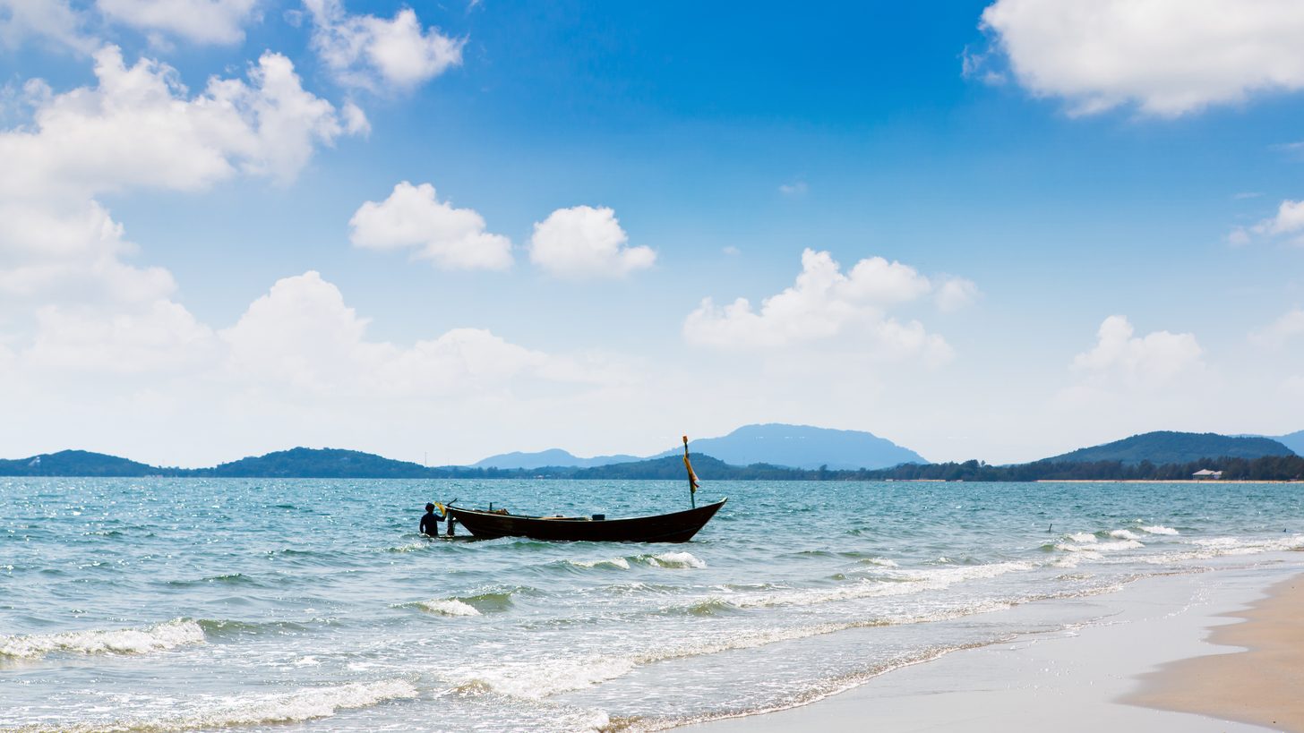 Traditional wooden boat just off a tropical beach in southern Thailand