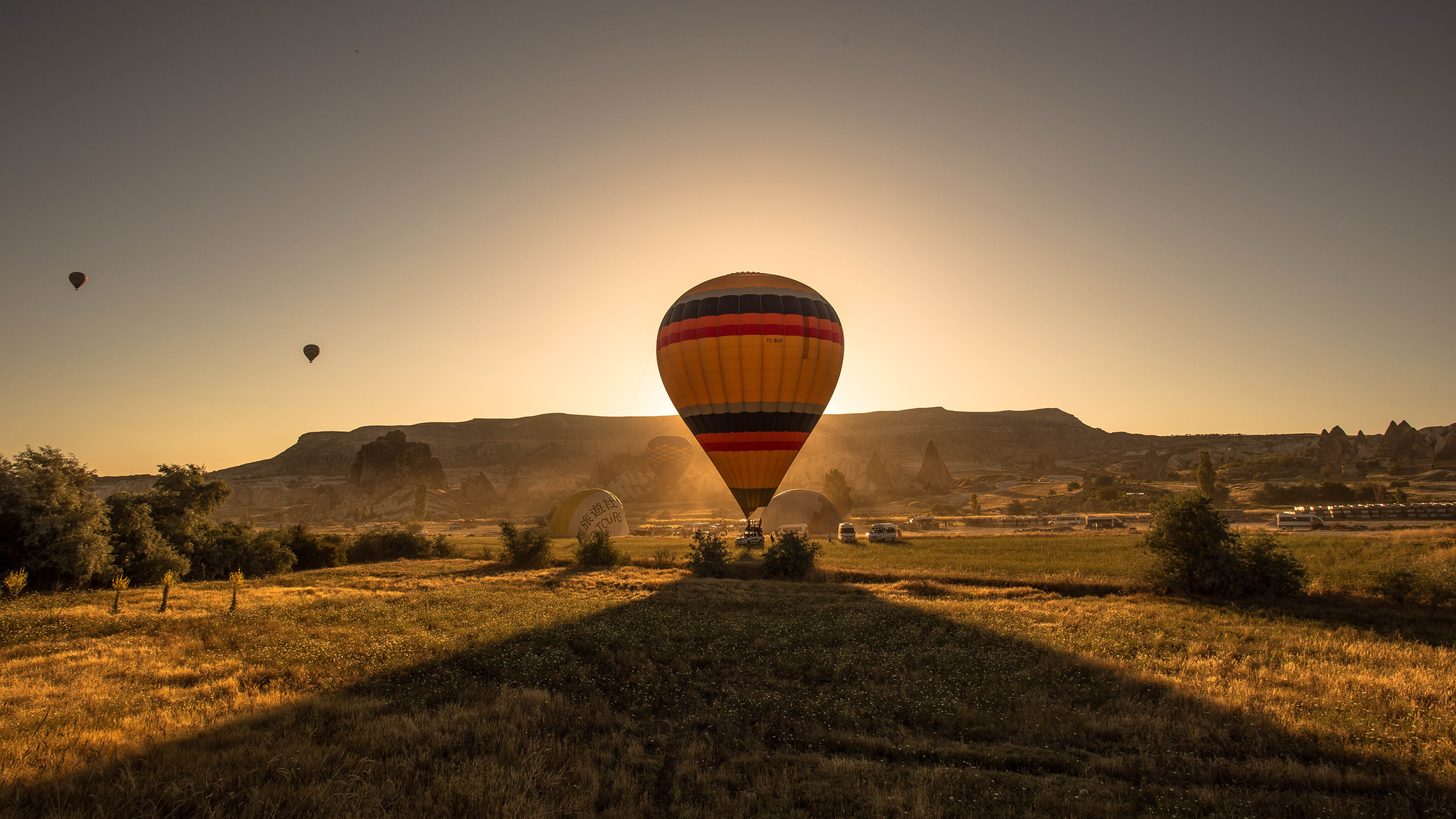 A hot-air balloon drifting over green hills and mountains
