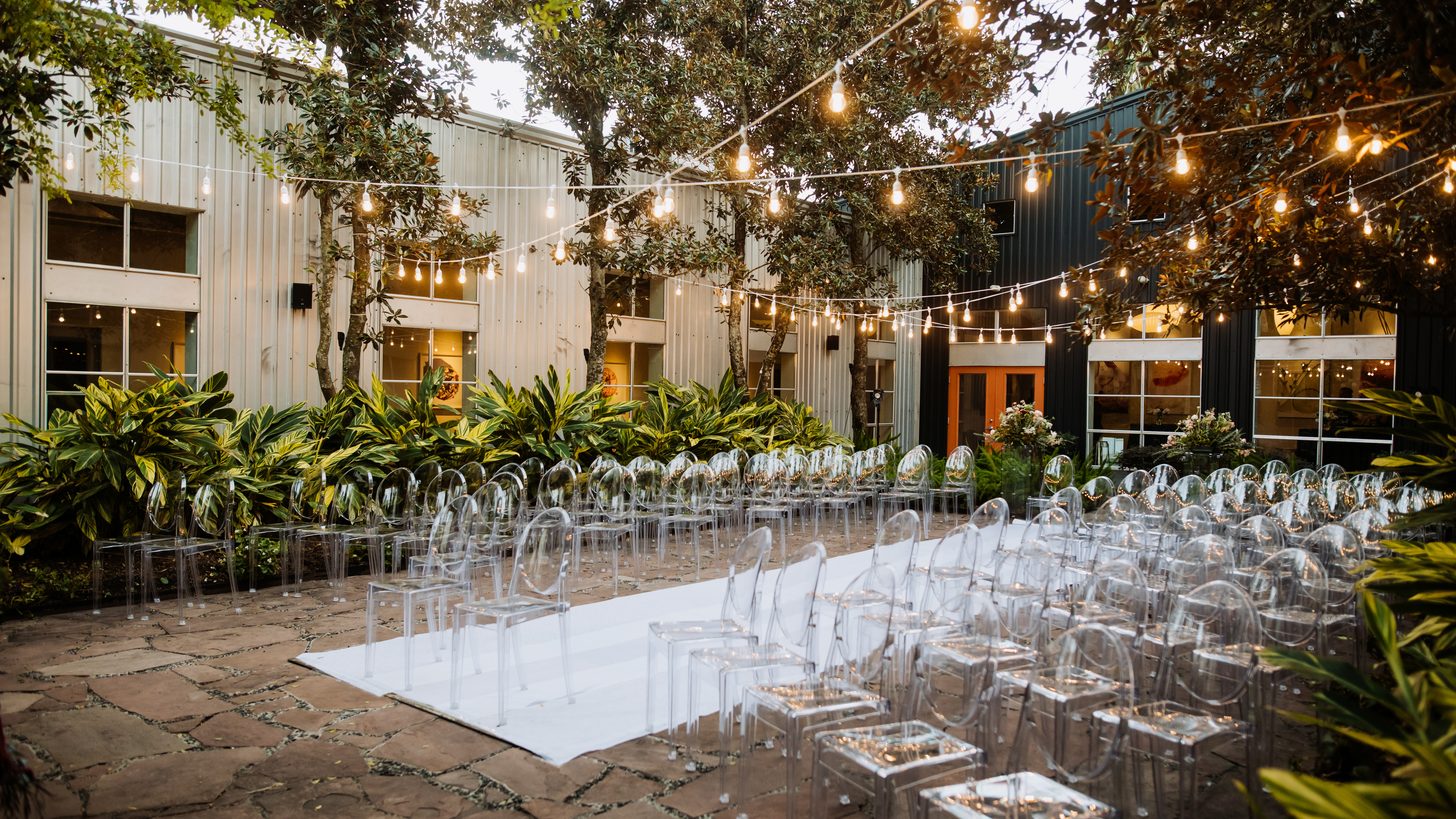 A decorated outdoor event area with chairs among trees