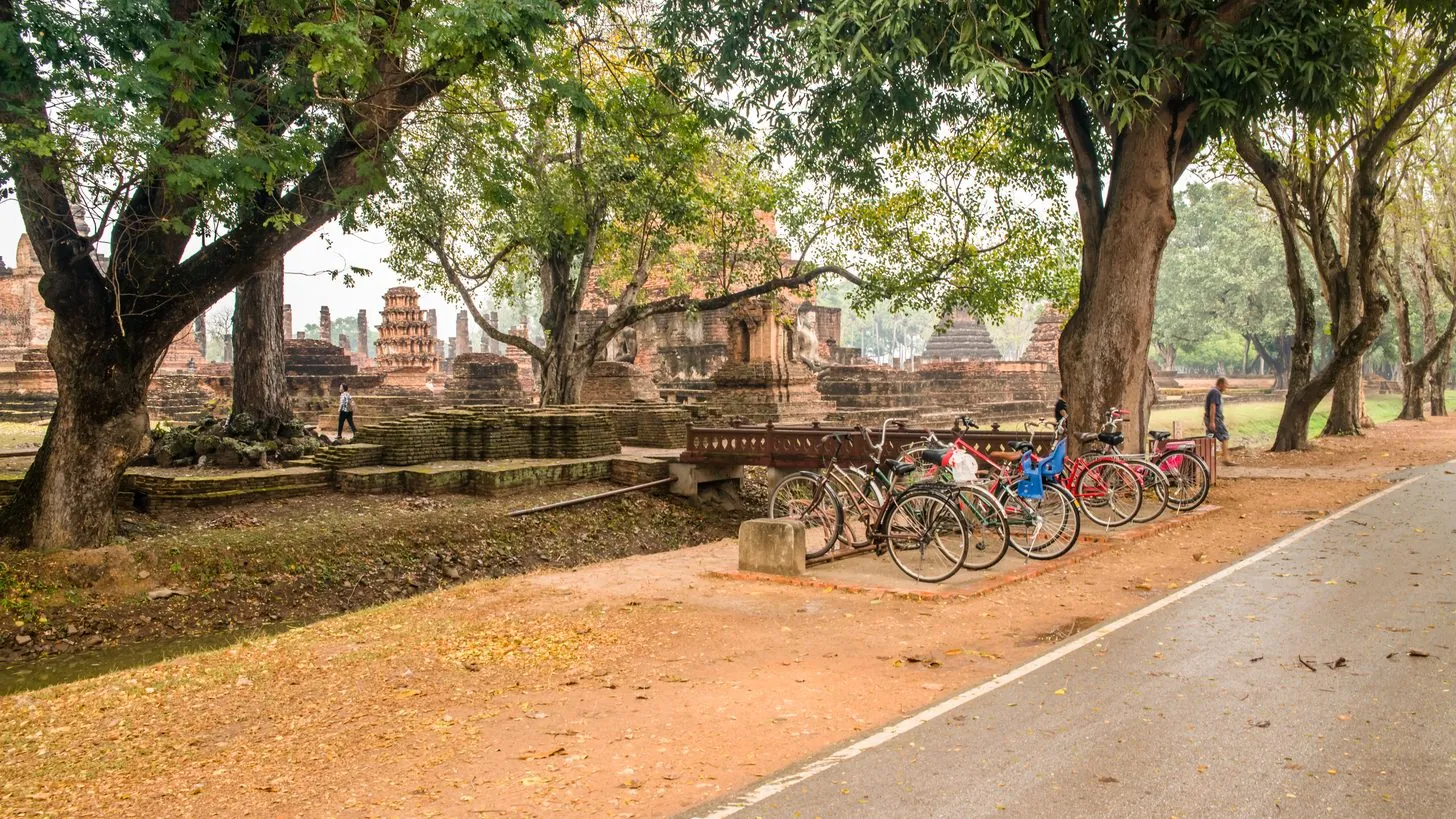 Sitzender Buddha und Lotusknospen-Stupa spiegeln sich in einem Teich im Sukhothai Historical Park