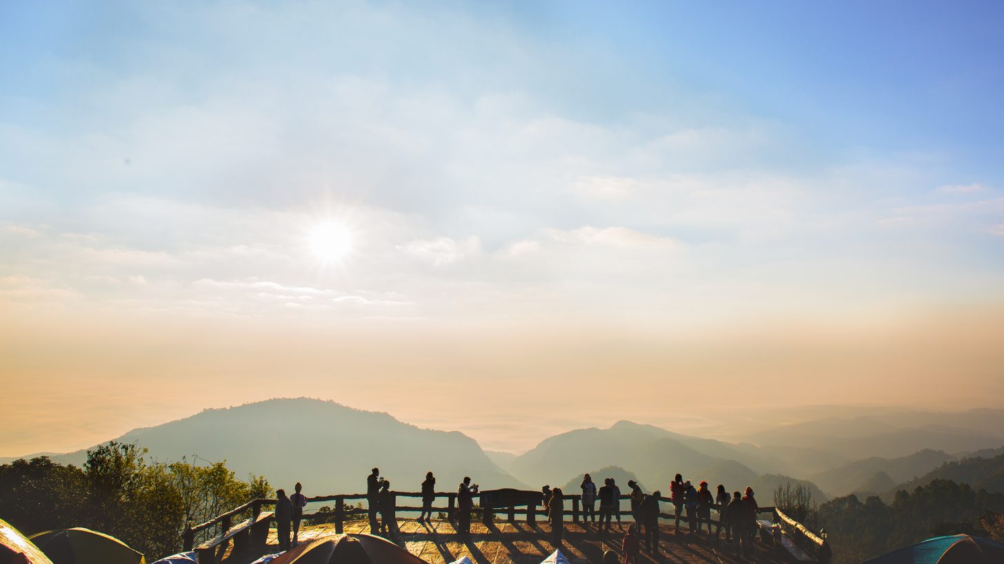 Silhouetted visitors watching the dawn from a mountain viewpoint