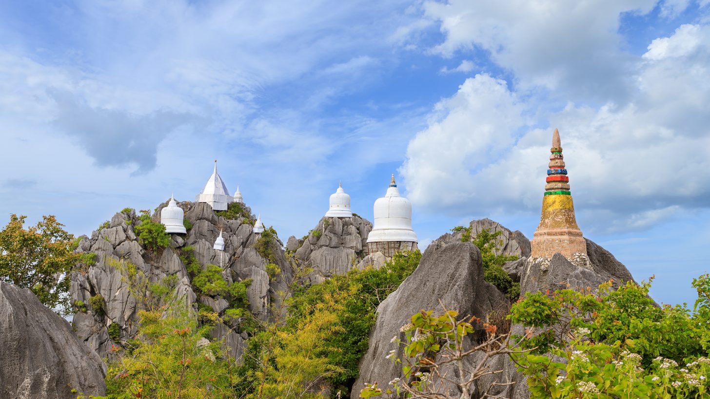 Pagodas on a mountain peak above forested hills in Lampang