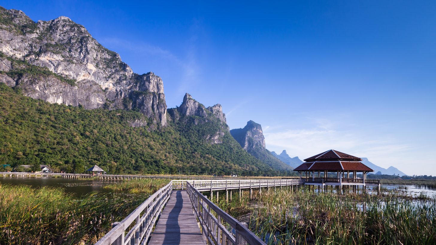 A wooden boardwalk crossing a lake between limestone hills in Sam Roi Yot