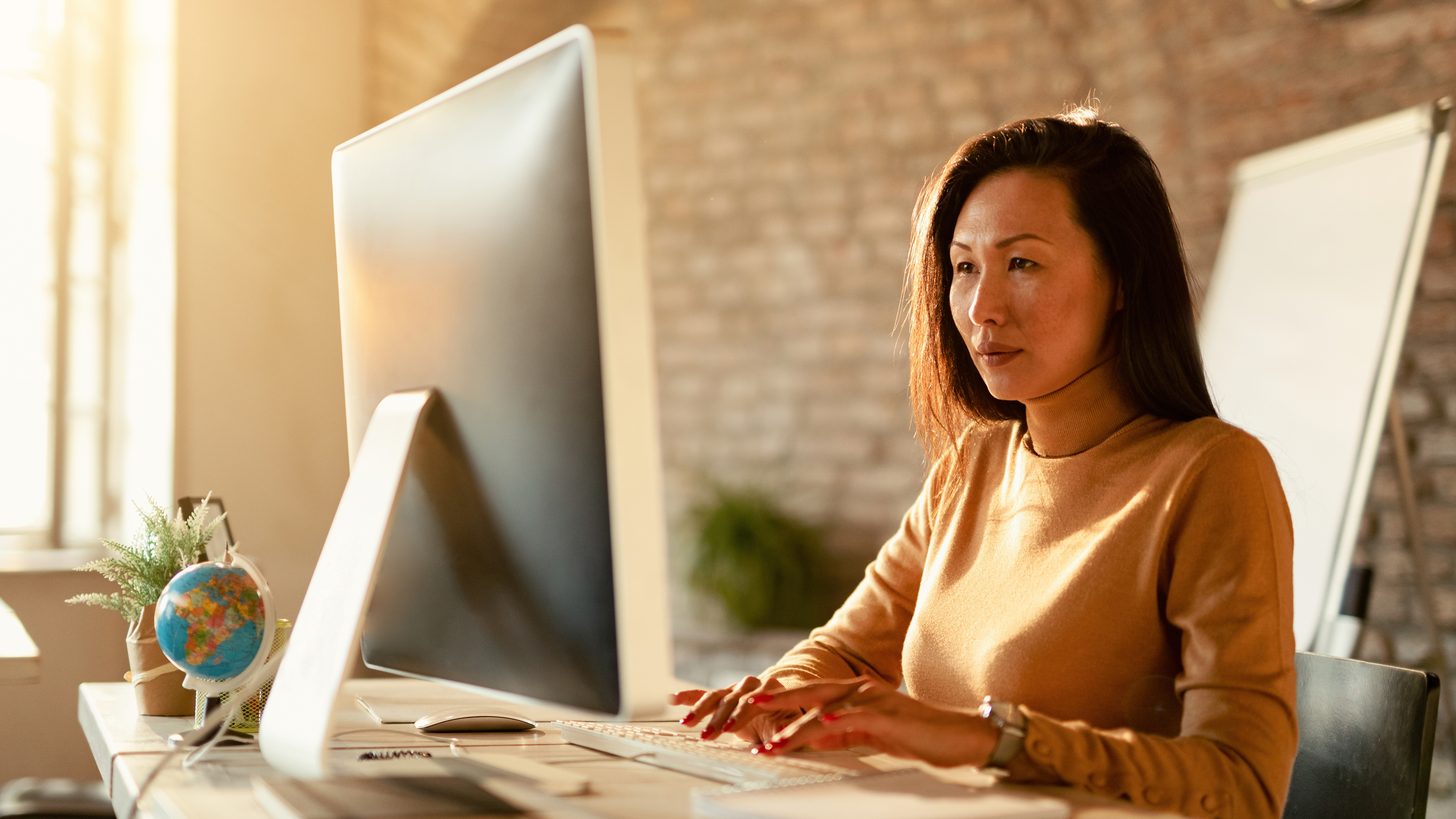 A travel agent working at a desktop computer in an office
