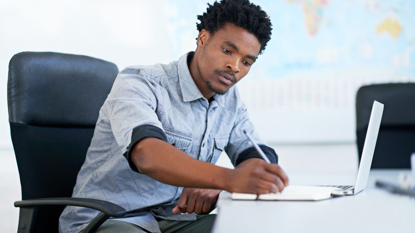 A travel agent reviewing notes and planning at a desk with a laptop