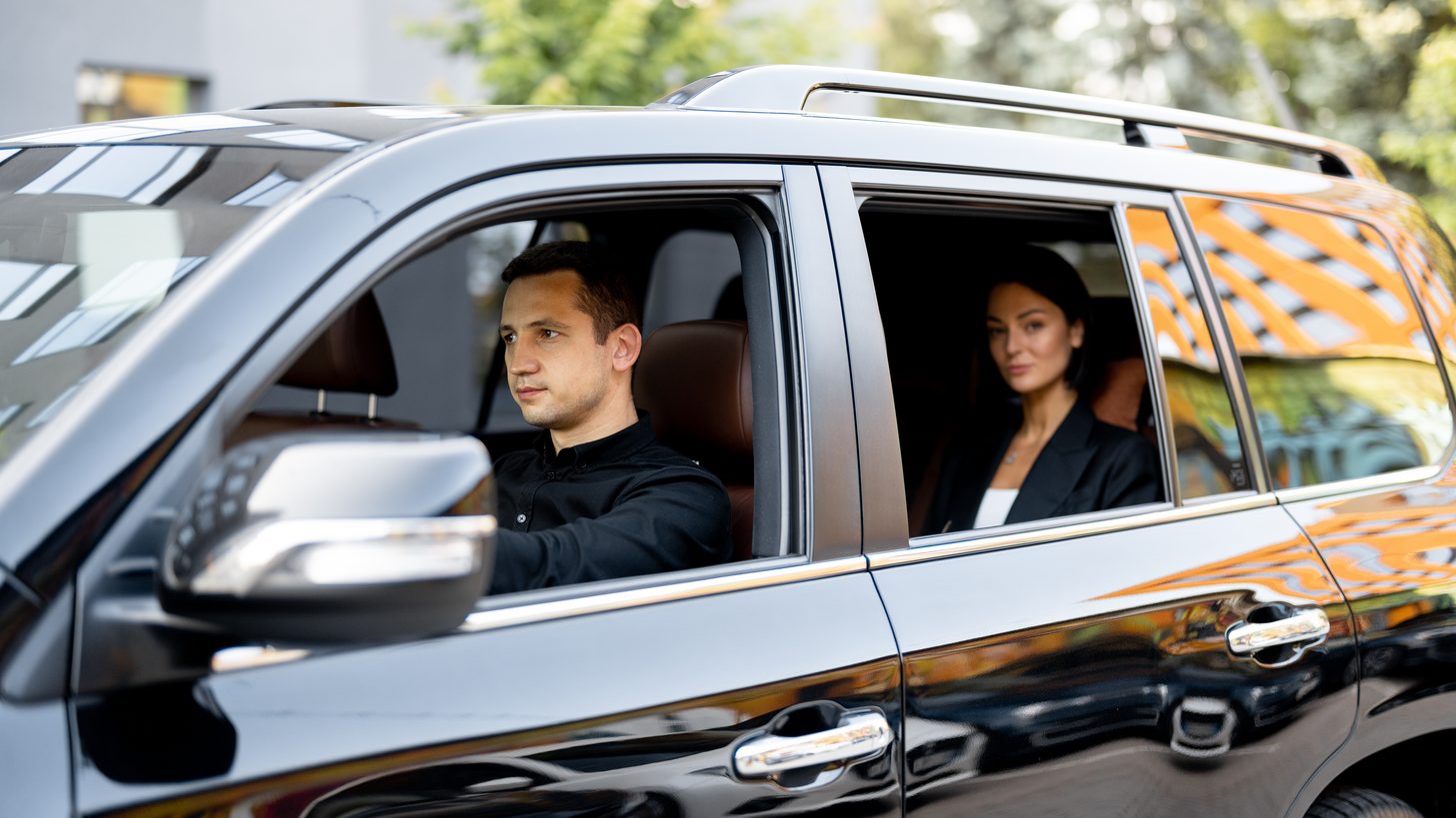 A professional driver with a client beside a premium vehicle