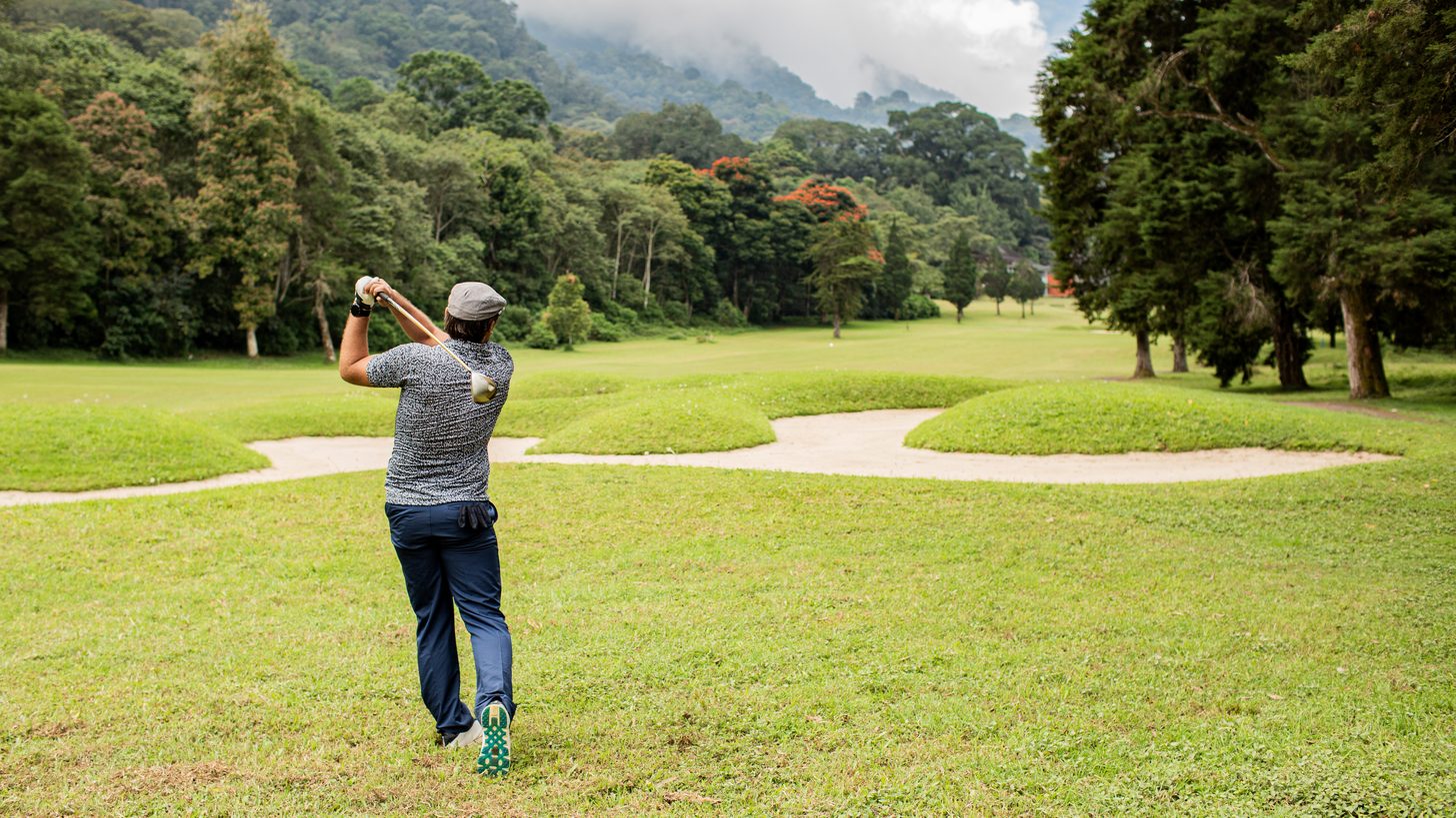 A golfer teeing off on a lush tropical course