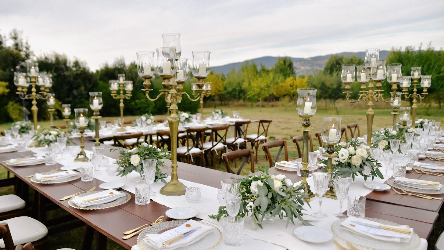 An elegant banquet table set outdoors for an evening event