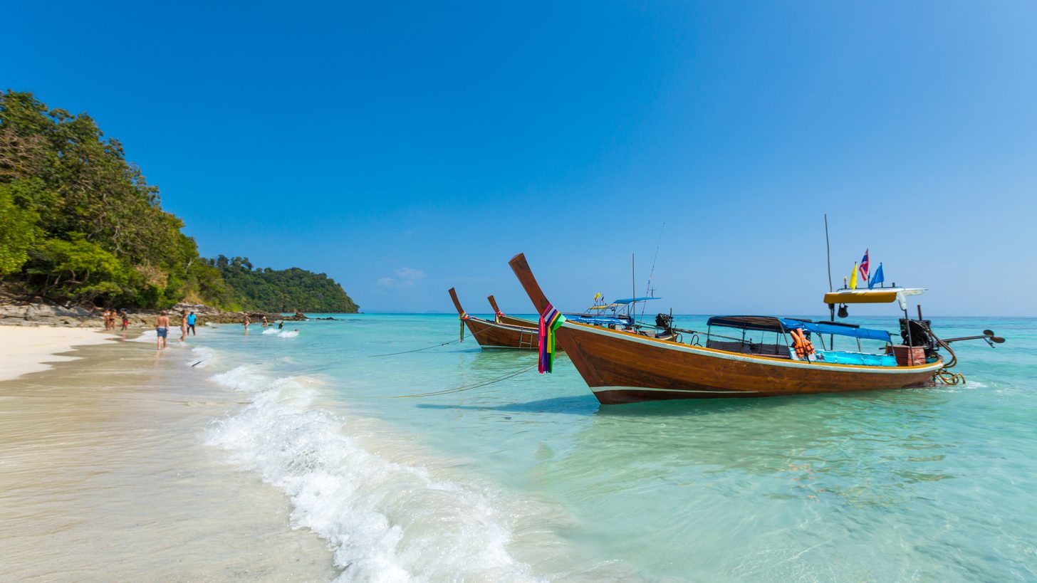 Longtail boats moored in a turquoise bay on Thailand's Andaman coast