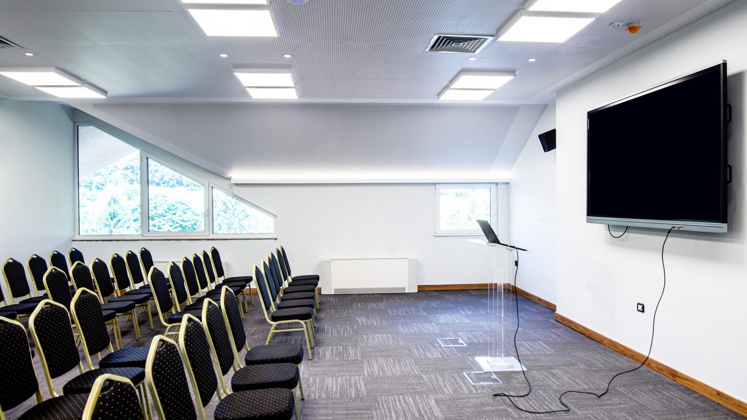 A daylight meeting room set theatre-style with a presentation screen