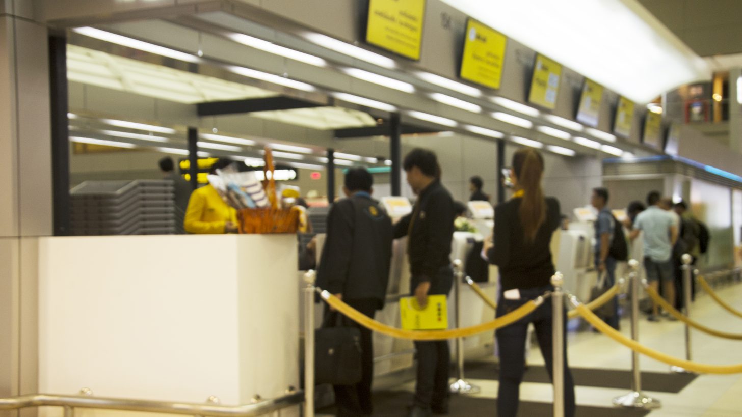 Domestic travellers queuing at check-in counters inside a Thai airport terminal