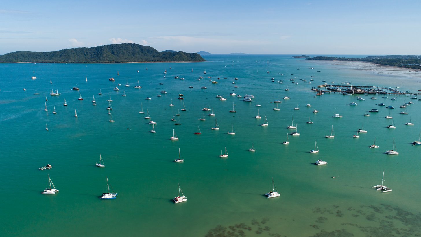 Yachts à moteur et voiliers amarrés le long des pontons d'une marina de Phuket, vus d'en haut en plein jour