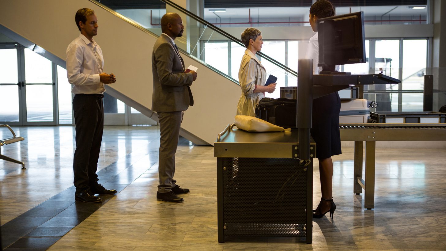 Passengers waiting in line with their luggage at an airport check-in counter