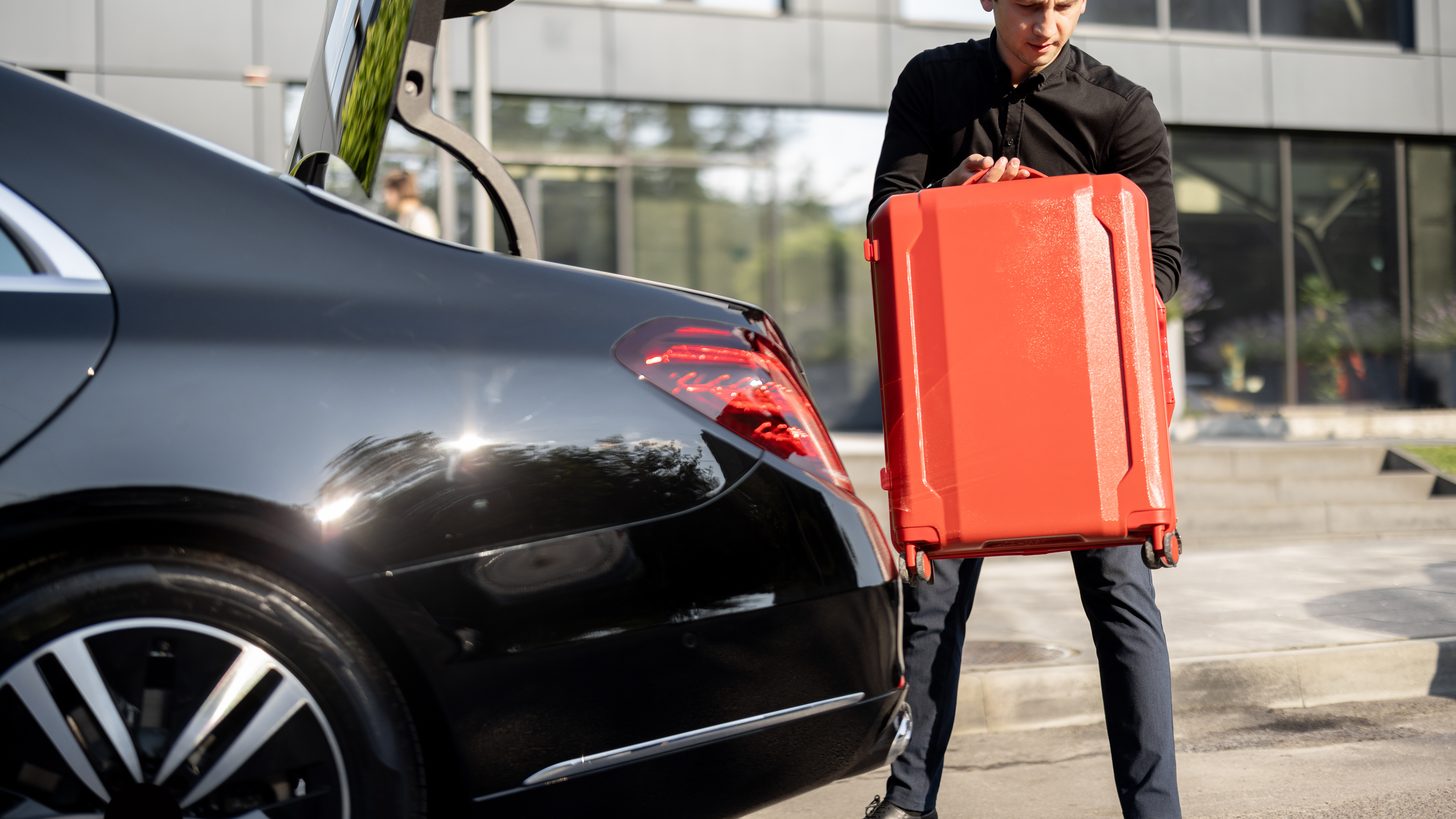 A private car and driver waiting at the gate of a residential villa in Thailand while luggage is loaded