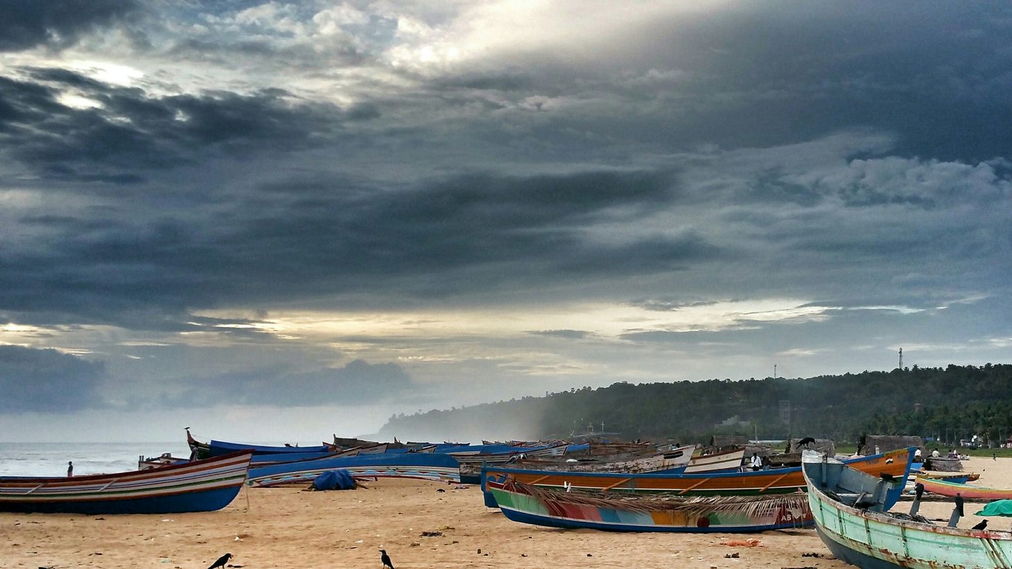 Boats moored close to shore under a heavy grey sky, with choppy water beyond