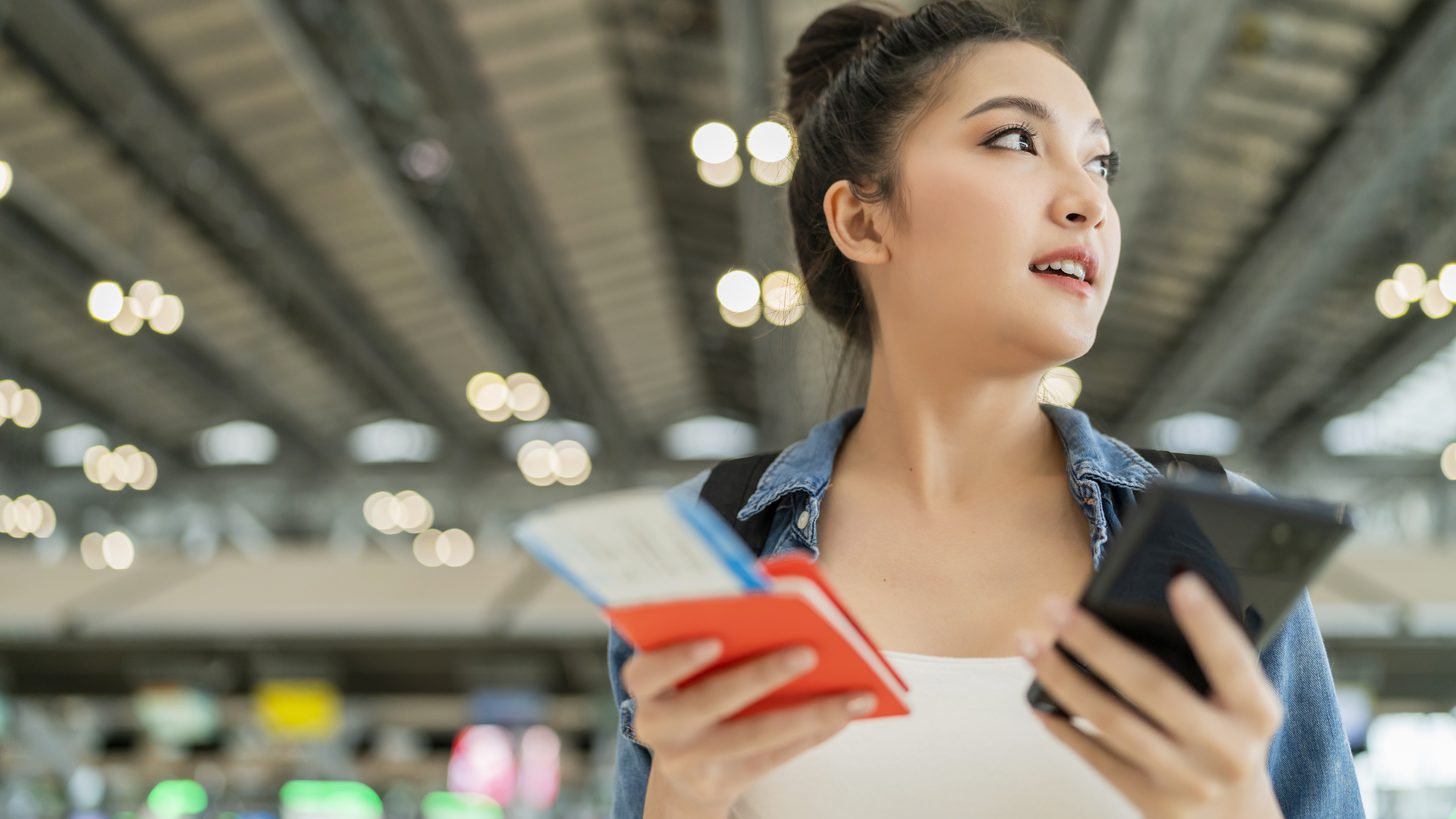 Traveller holding a passport and a phone in an airport terminal