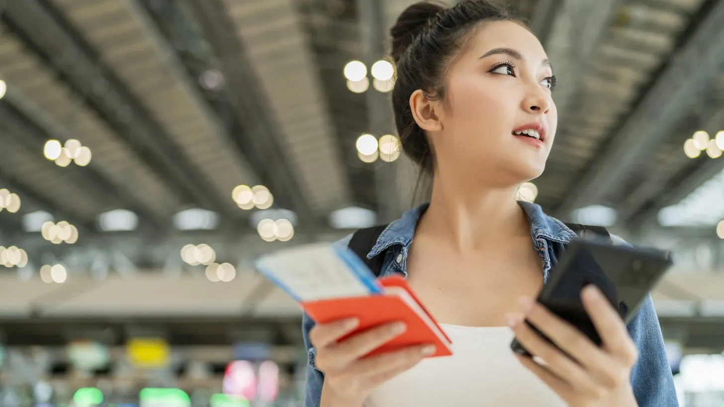Traveller holding a passport and a phone in an airport terminal