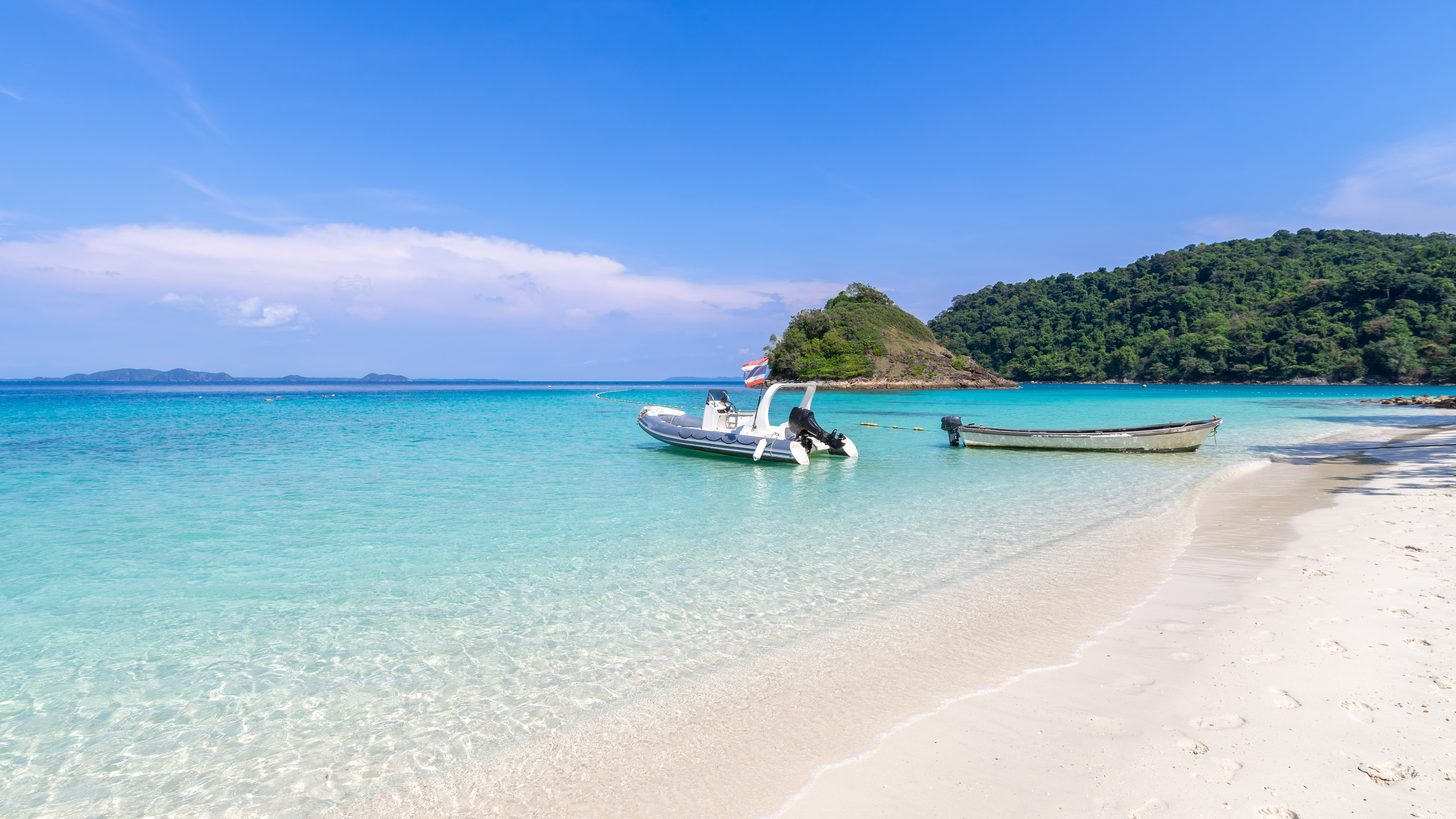A quiet island beach with clear water under a blue sky in eastern Thailand
