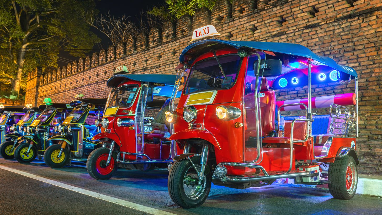A traditional Thai tuk-tuk taxi waiting on a city street