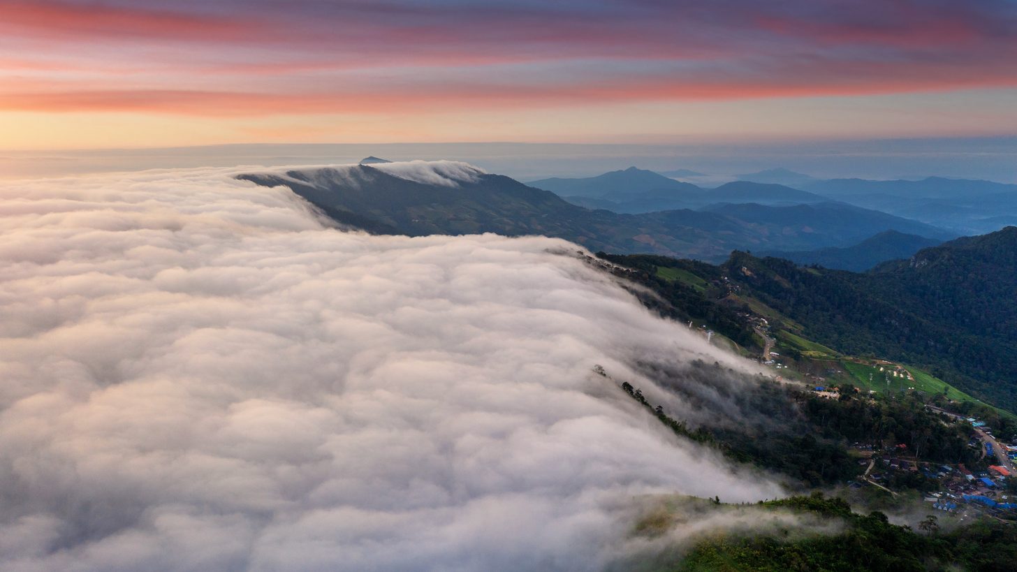 Morning fog lying over layered mountain ridges at sunrise