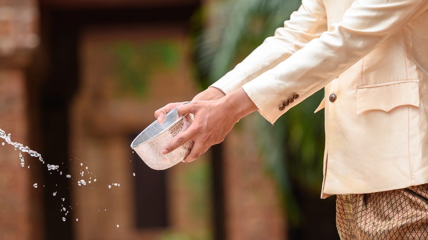 A man pouring water from a bowl during Songkran at a temple