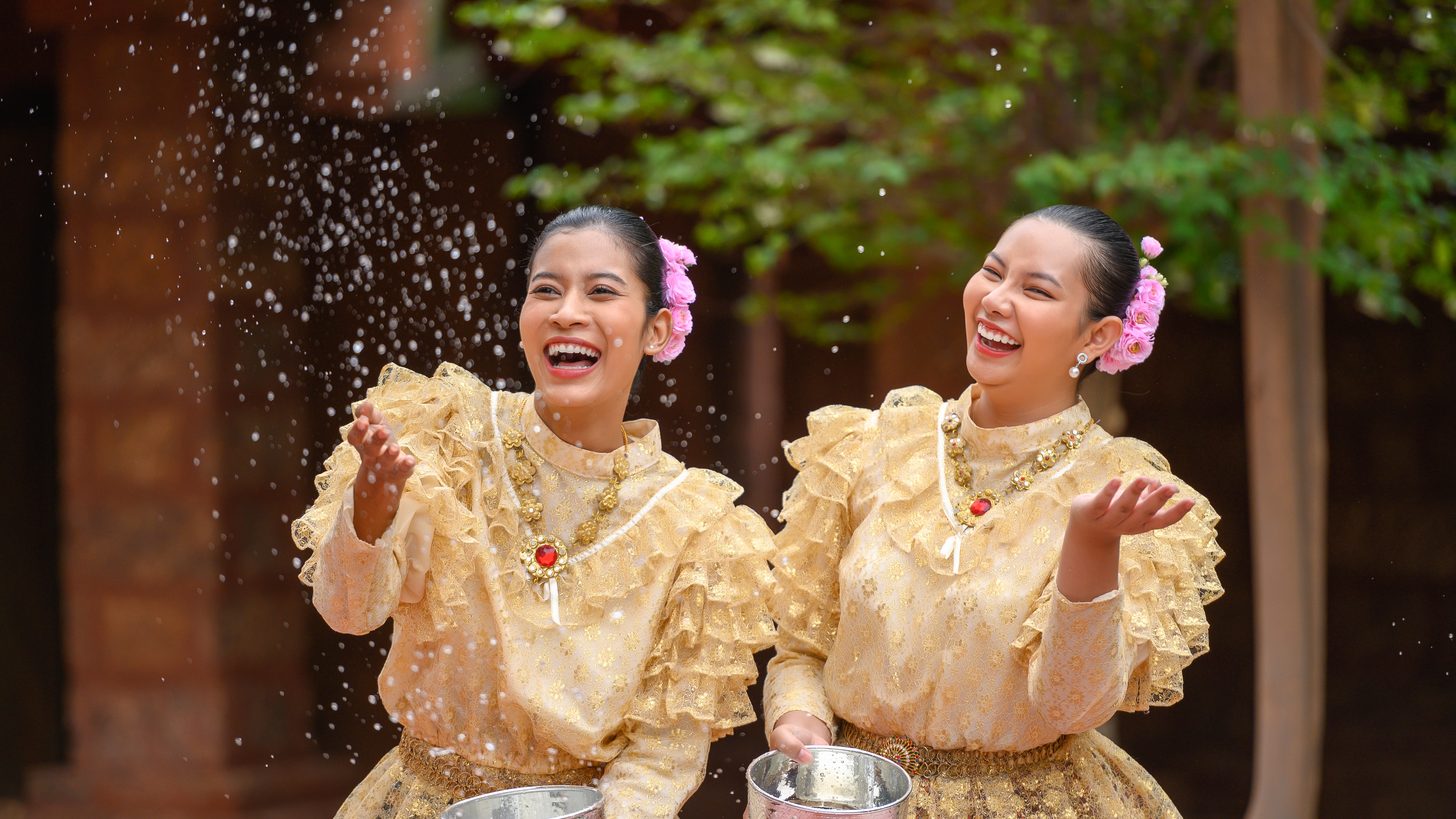 Women in traditional Thai dress taking part in a Songkran water blessing