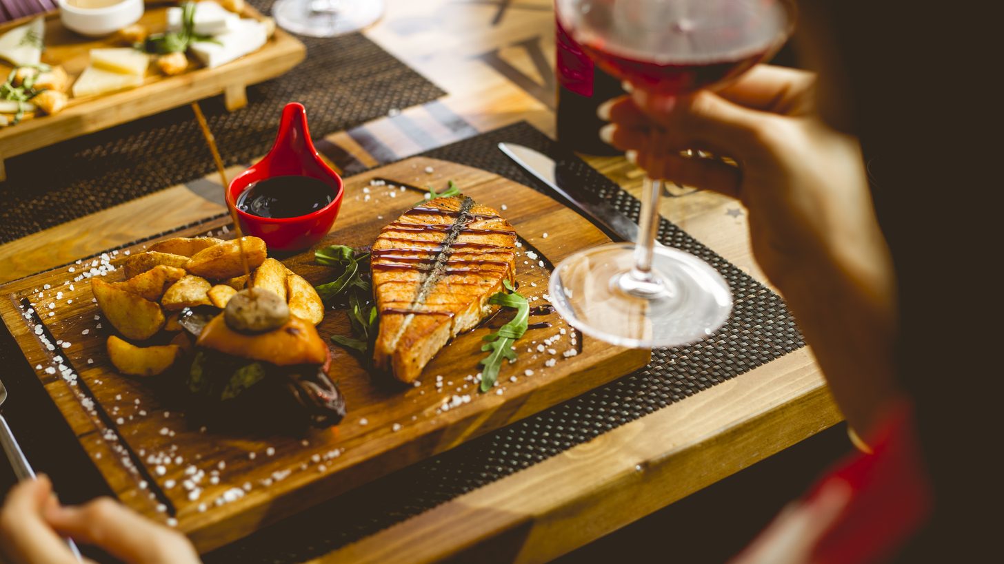A plated fish course served with a glass of white wine