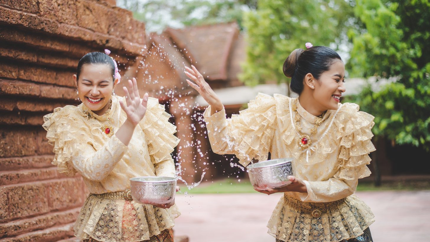 Women in Thai dress pouring water at a temple during Songkran
