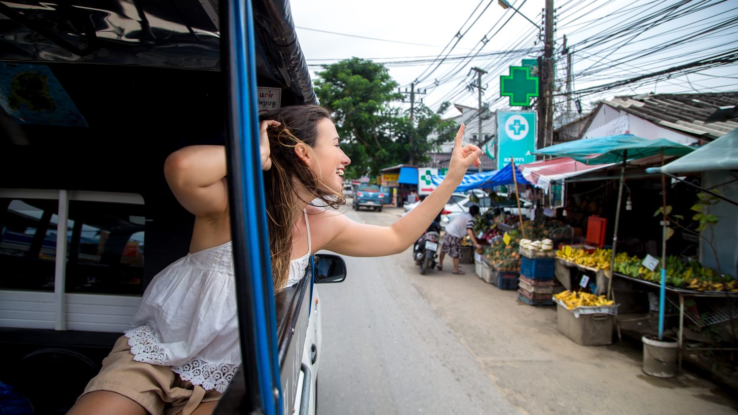 A traveller riding in a tuk-tuk through a Thai city street