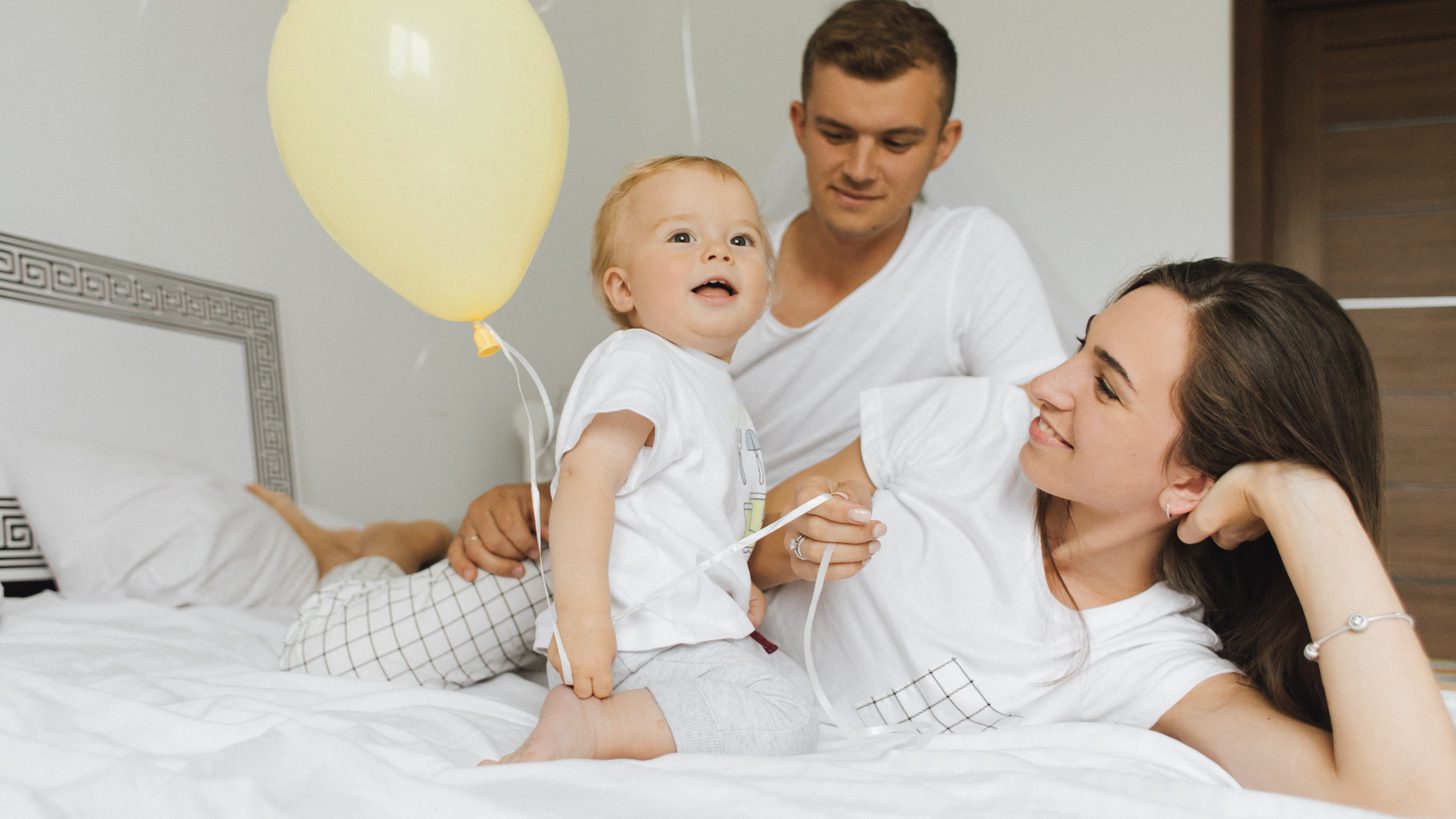 A family with a small child in a bright hotel room in the morning