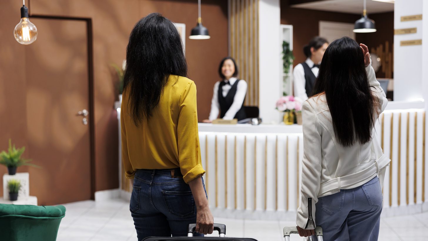 Travellers arriving with luggage at a hotel front desk