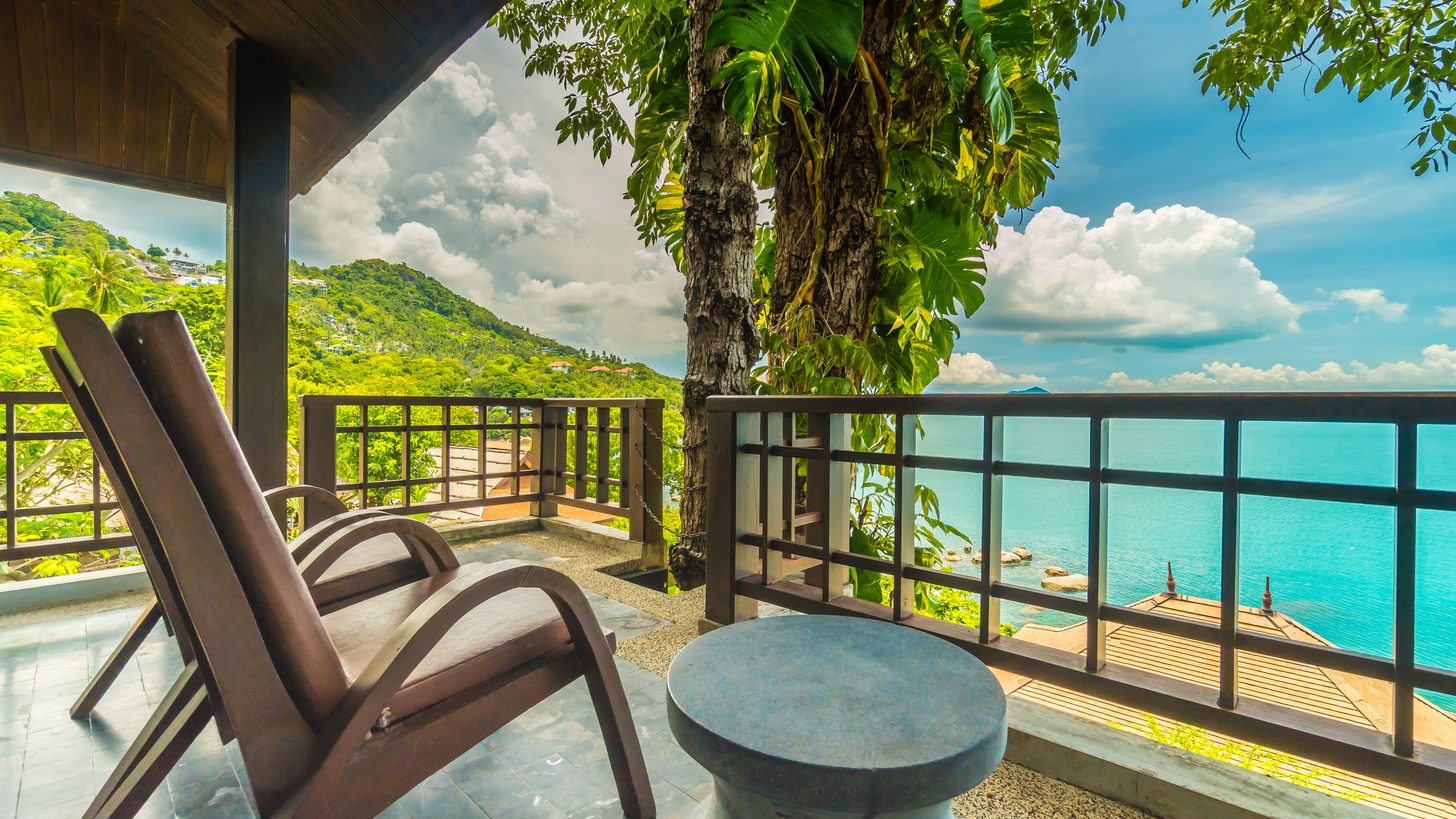 A resort balcony with seating overlooking the sea