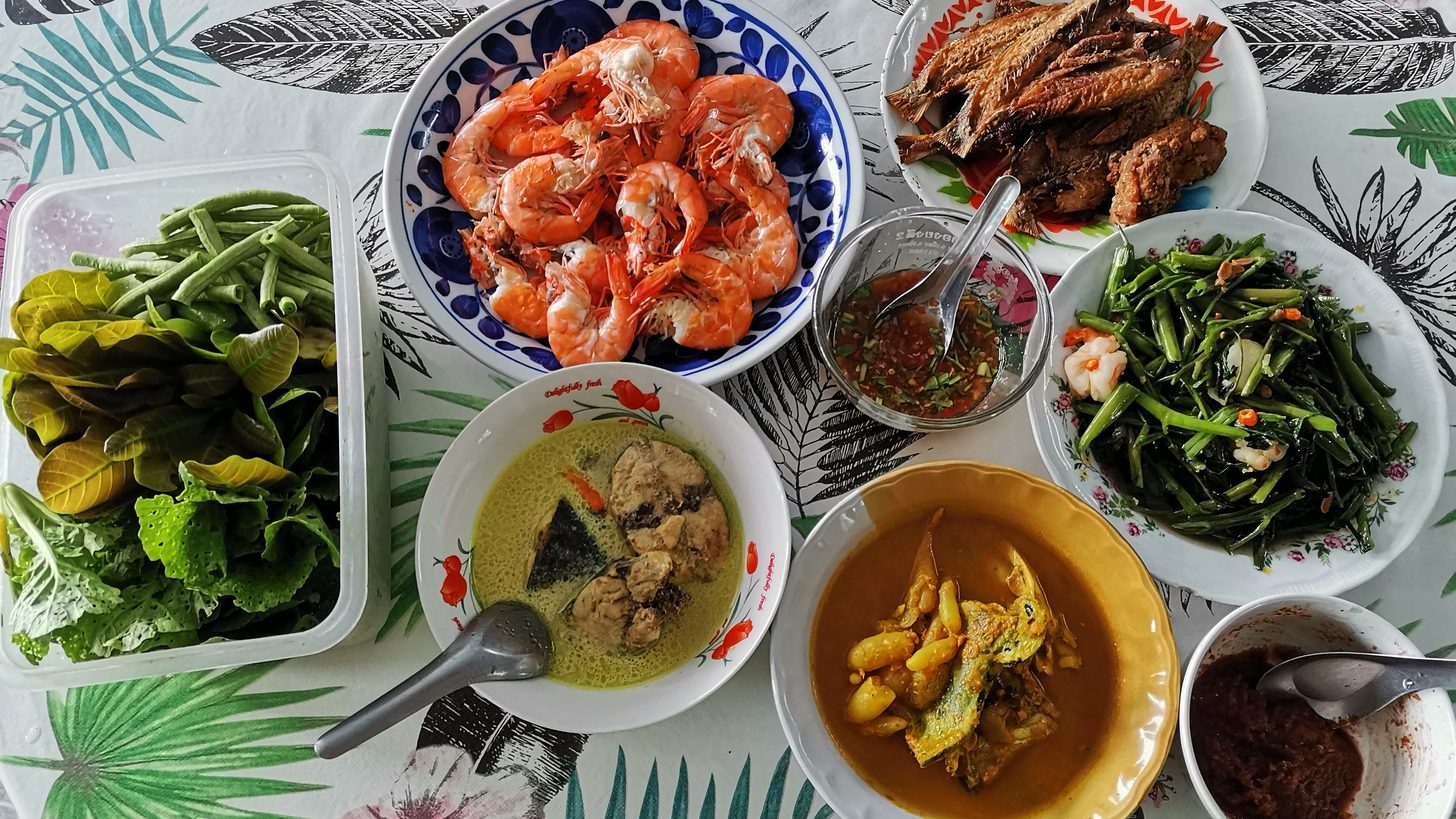A Thai chef plating dishes in a restaurant kitchen
